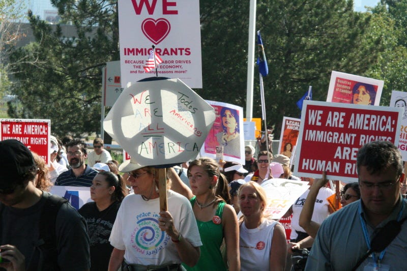 Protesters hold up signs demanding rights for immigrants.
