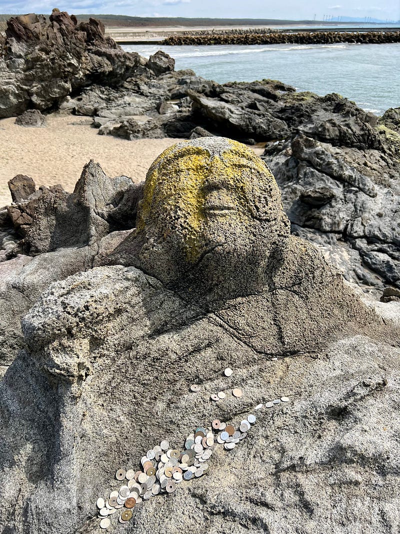 Pleasant-faced statue carved in stone outcrop on the beach.