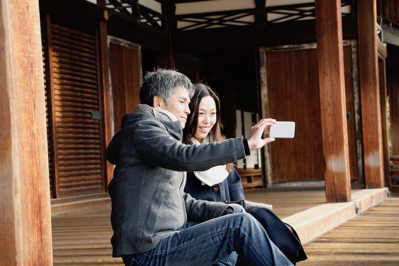 A couple in Japan take a selfie with their smartphone at a temple