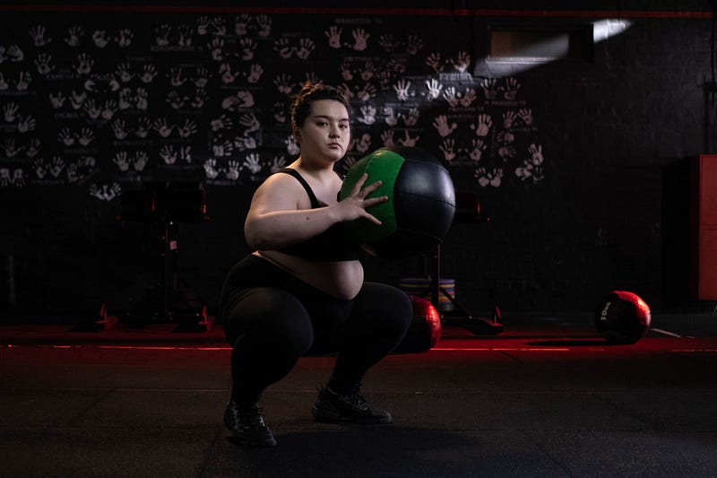 A woman doing body-weigh squat with medicine ball.