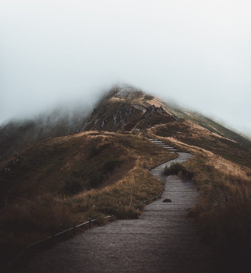 Twisting path along a mountain ridge, disappearing into fog