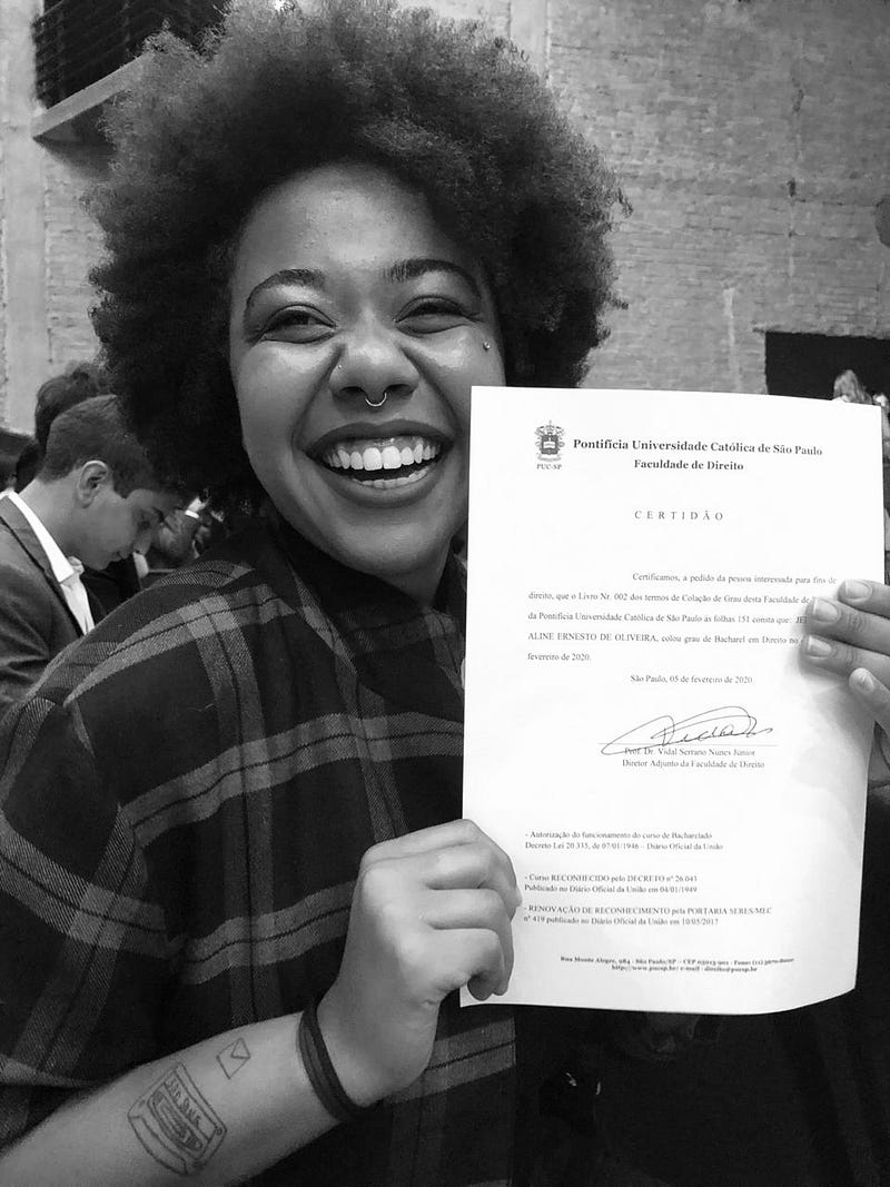 Uma foto da Jennifer Ernesto segurando o certificado de Colação de Grau na Faculdade de Direito da PUC-SP