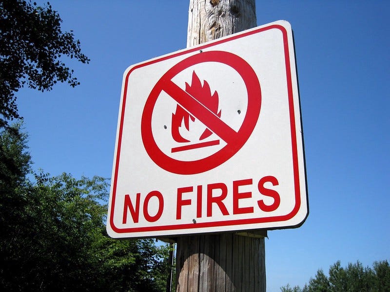 A sign that says NO FIRES with a symbol of a fire struck through.