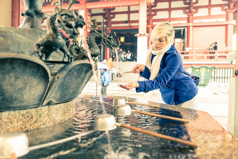 A woman purifies herself at the temizuya in front of Hakone Shrine