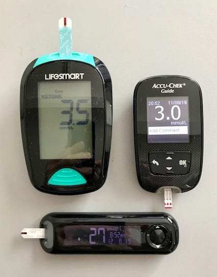 Two blood glucose meters, one showing 3.0 mmol/L and the other 2.7 mmol/L, one ketone meter showing 3.5 mmol/L.