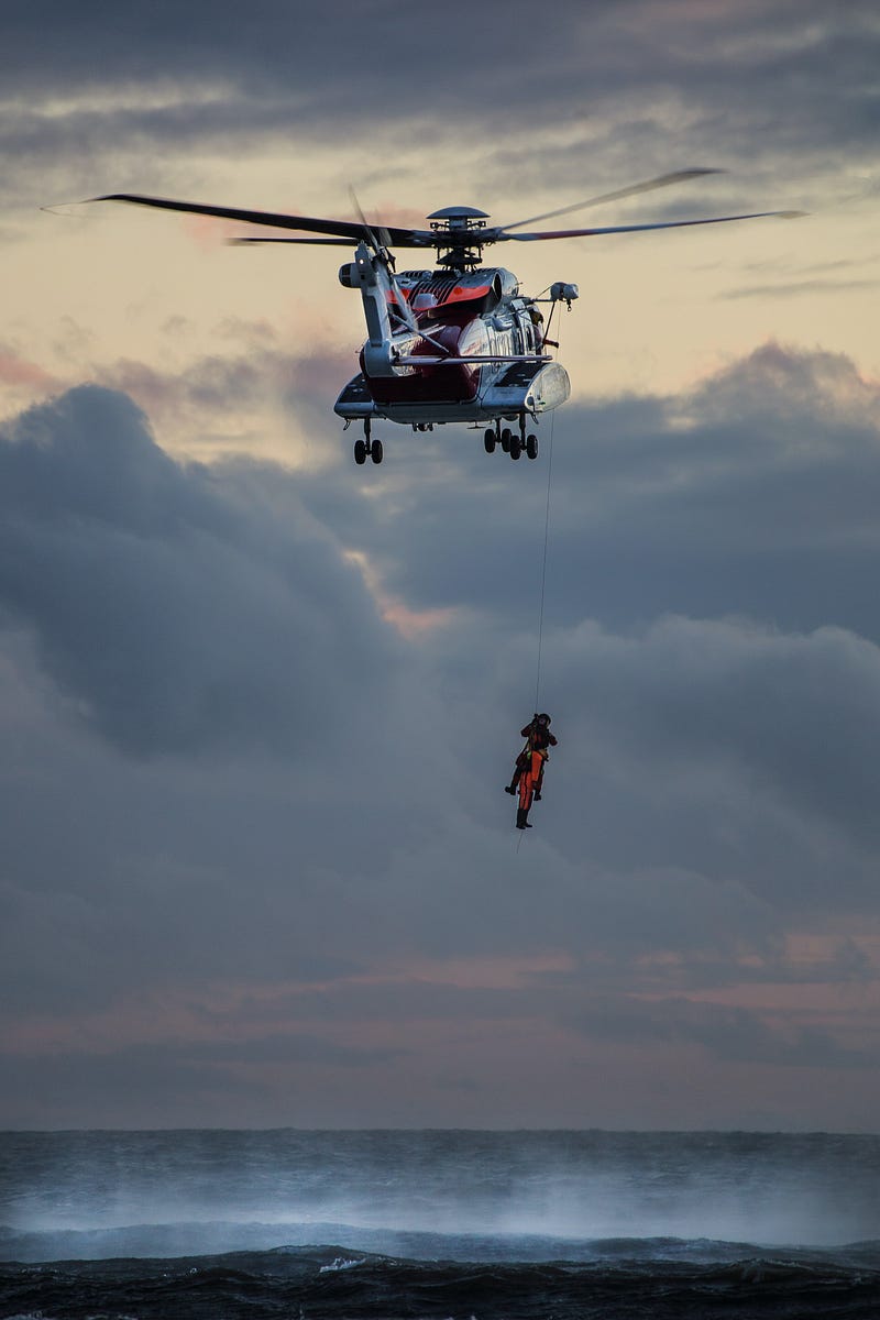 Helicopter rescue over calm blue sea.