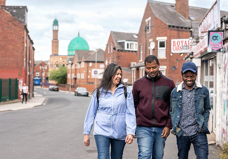 Three students in the Hyde Park area of Leeds, a short walk from the University of Leeds campus. The mosque is visible in the distance.