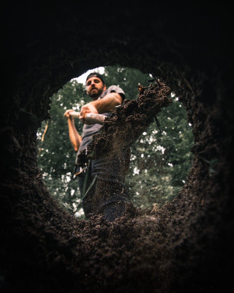Man filling a hole with a shovel.