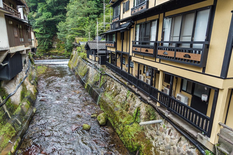 A traditional ryokan in Japan that has an onsen by the river