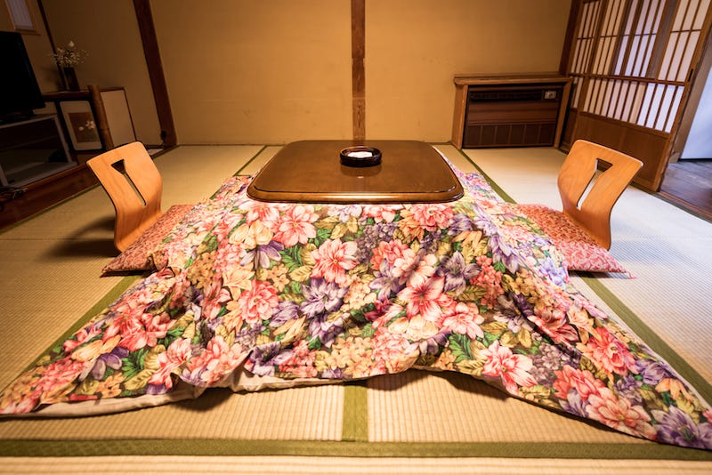 A Japanese kotatsu, essentially a modern form of the irori, sits on top of a tatami-floored room.