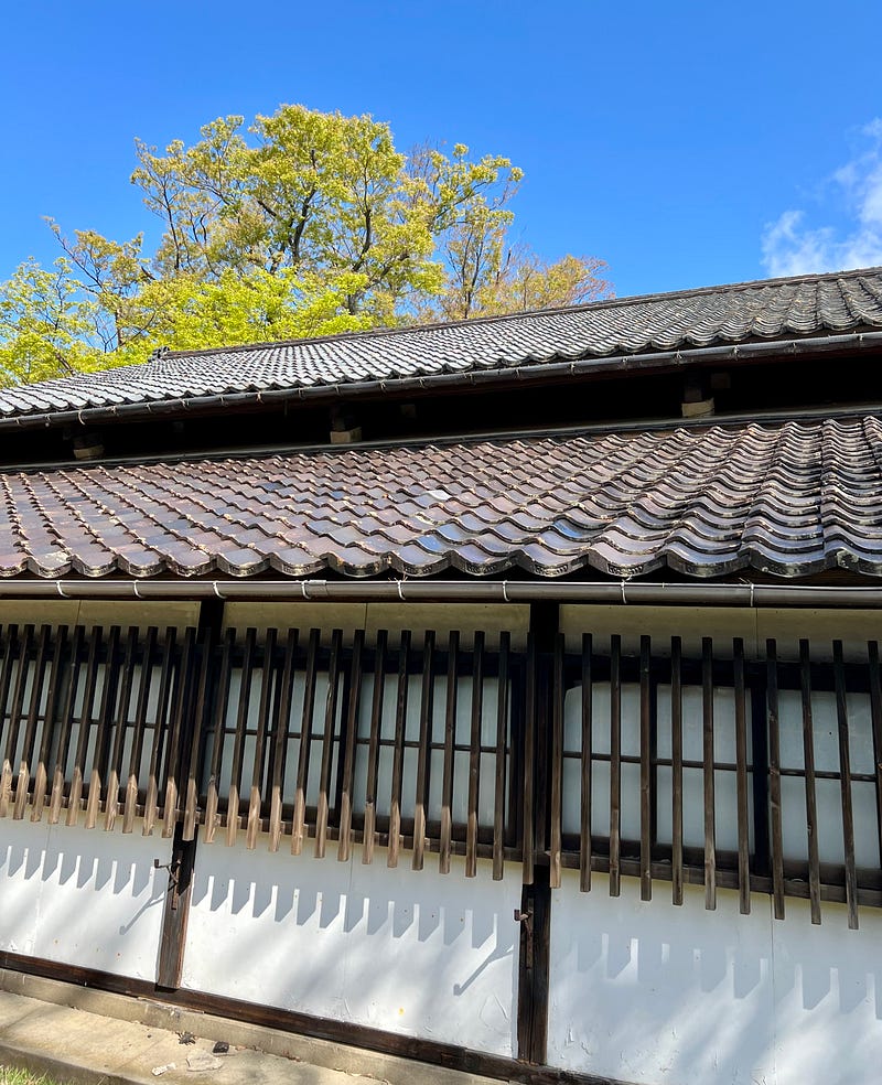 Double roof of storehouse. Trees and sky behind. Sankyo rice storehouses, Sakata, Yamagata.