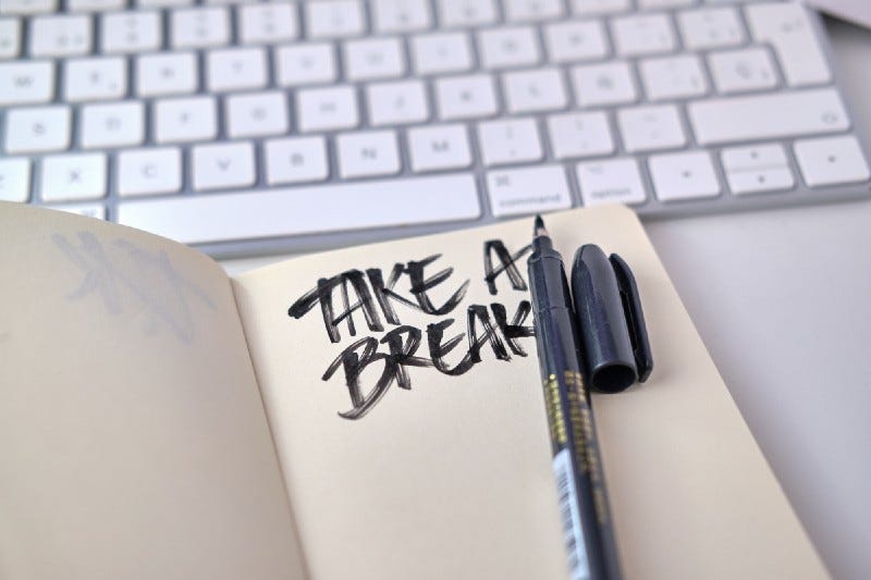 Note pad in front of a computer that has “Take a break” scribbled on it