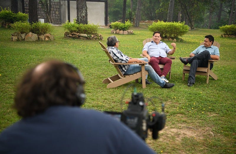 Three adult Honduran men discuss ways to support the LGBTQI+ community while a cameraman films the conversation.