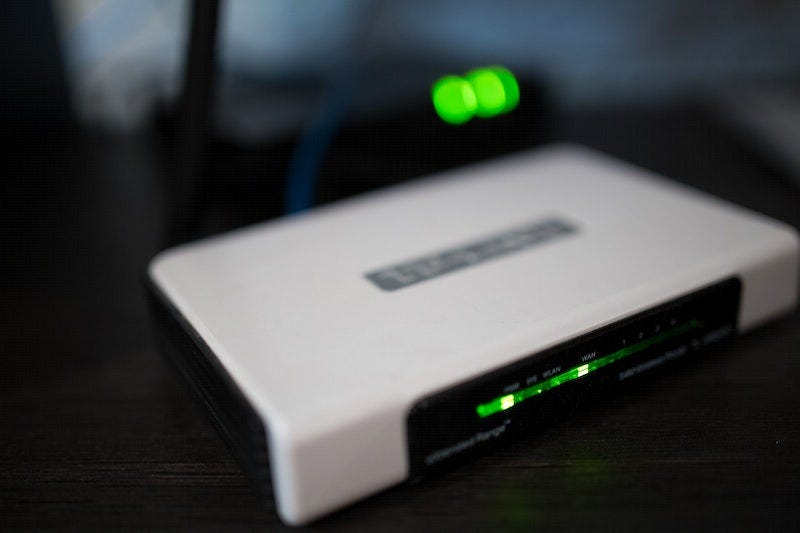 A white colored router with its green colored lights on.