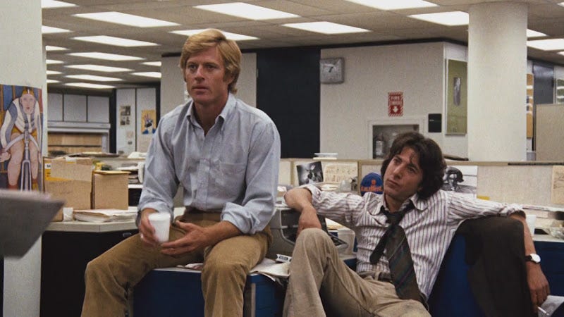 Still from the movie All the President’s Men. Robert Redford and Dustin Hoffman casually sit in a newsroom.