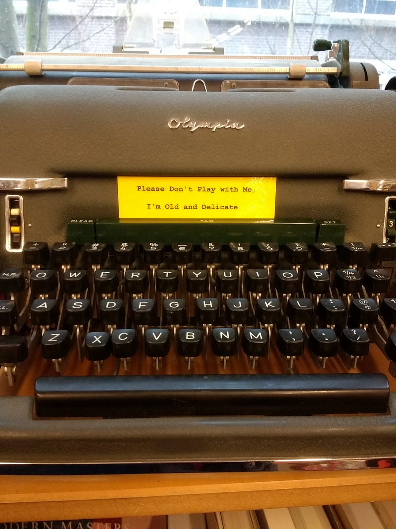 typewriter with a sign that reads "Please don't play with me I'm old and delicate."