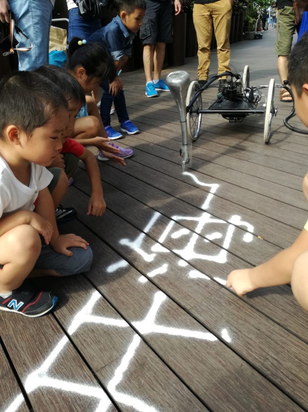 オランダのGijs van Bon{.markup–anchor .markup–figure-anchor}によるSandwriter Robot。砂で地面にポエムを描いていく。今回は台風でホテルに閉じ込められている間に、漢字で書くように調整していた。「日本でもやりたいので、招待をお待ちしている」とのこと。(撮影:伊藤亜聖)