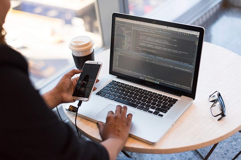 Working on a laptop while holding a phone