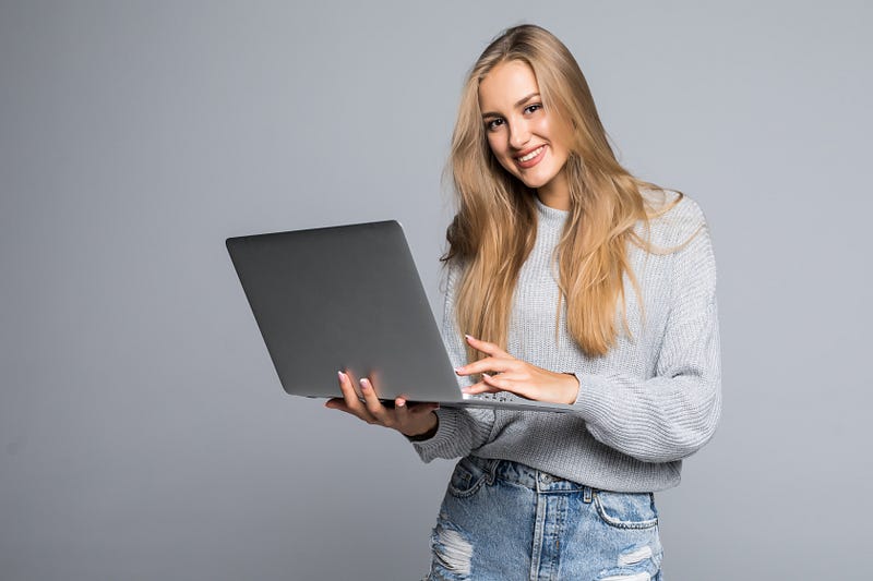 Attractive young woman with laptop smiling in camera.