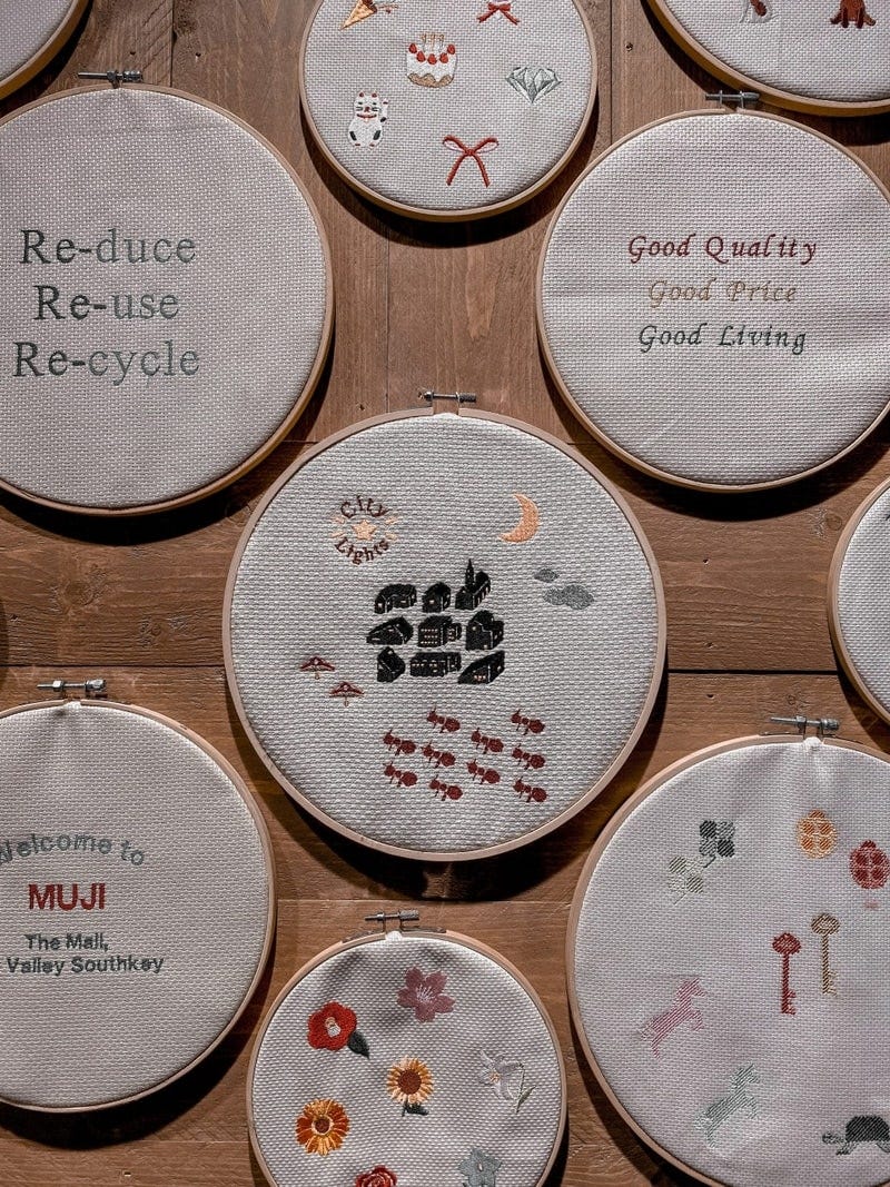 A series of embroidery hoops. Some have small symbols of plants, bugs, and factories, other have sayings such as ‘reduce reuse recycle’ and ‘good living’