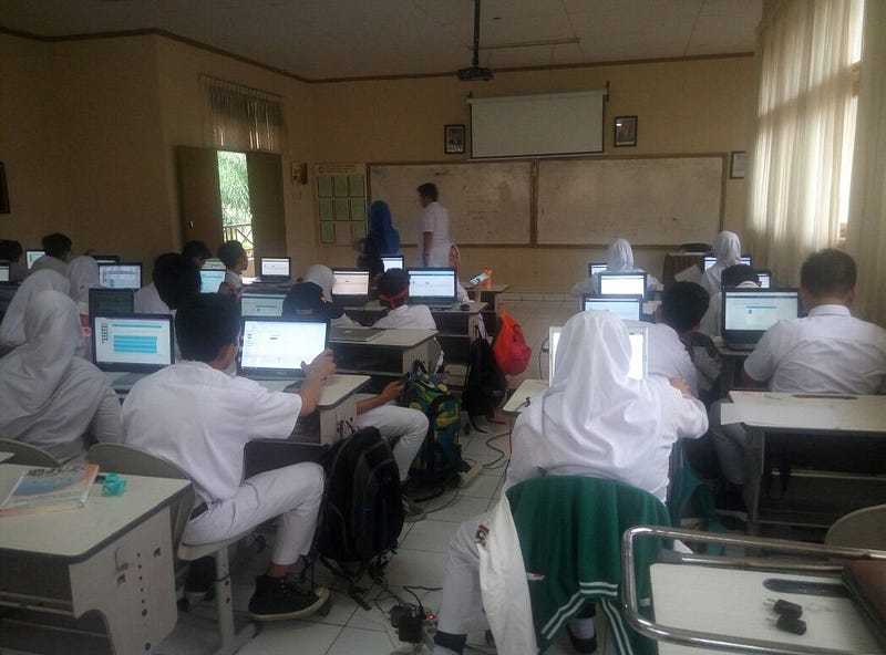 para siswa sedang melaksanakan ujian secara digital via laptop masing-masing dengan bantuan alat Edubox