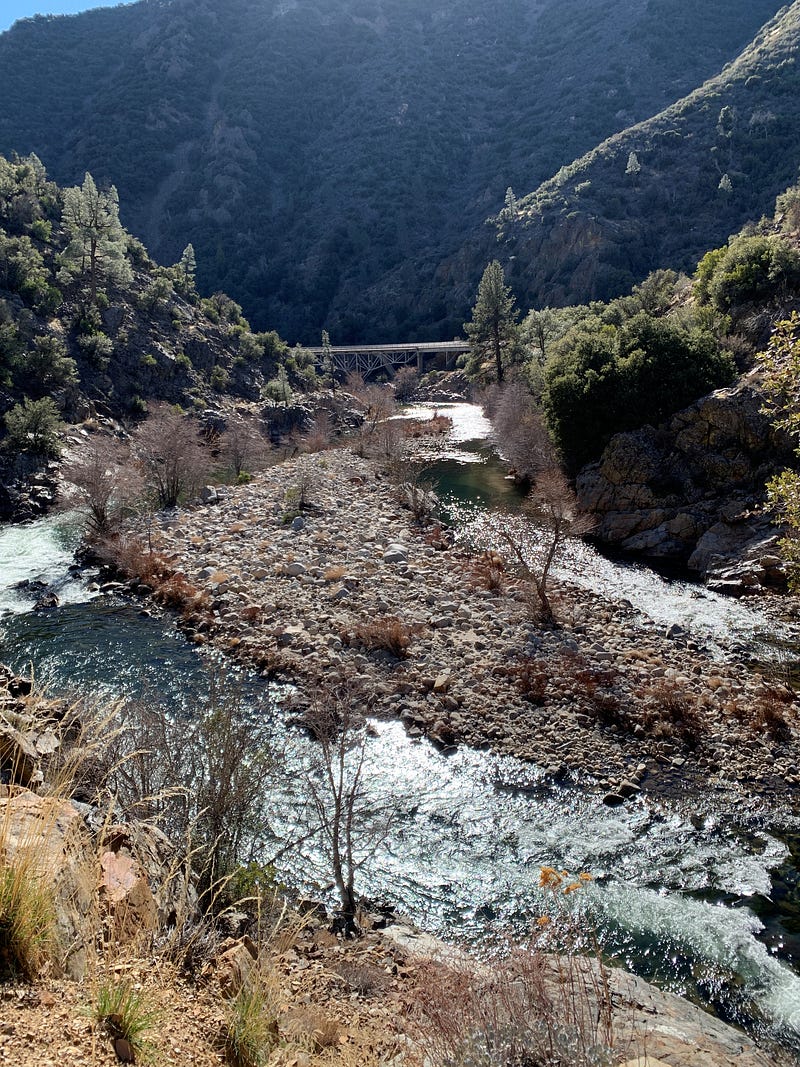 Casting memories Fly fishing: river and mountains. Scenic river landscape with rocky banks and a bridge in the distance, perfect for a fly fishing adventure