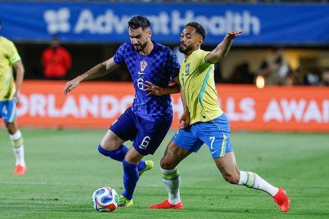 Josip Sutalo dan Matheus Cunha berebut bola dalam laga uji coba internasional antara Brasil vs Kroasia di Camping World Stadium, Florida, 1 April 2026 © AP Photo/Kevin Kolczynski