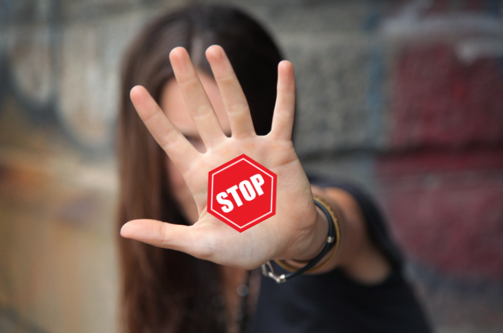 Stop The Overwhelm! — Create A Social Media Content Plan Instead. Young woman with brown hair raises hand with a sticker on it saying: Stop!