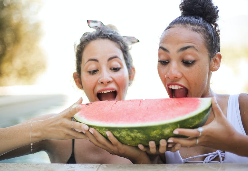 Two women eating a watermelon.