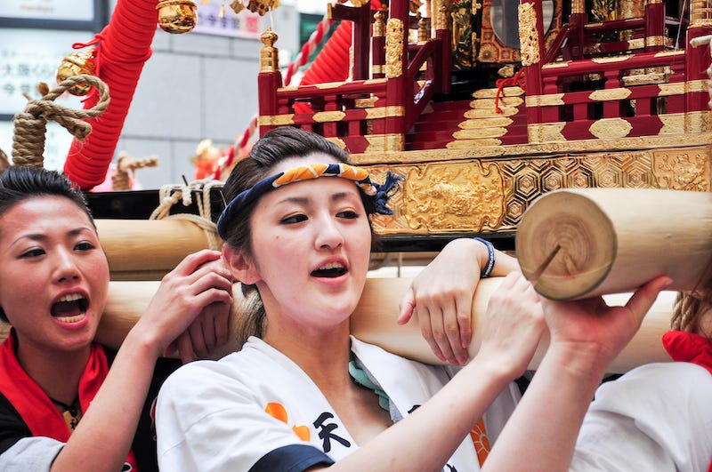 A group of female participants in a Japanese festival carry a mikoshi