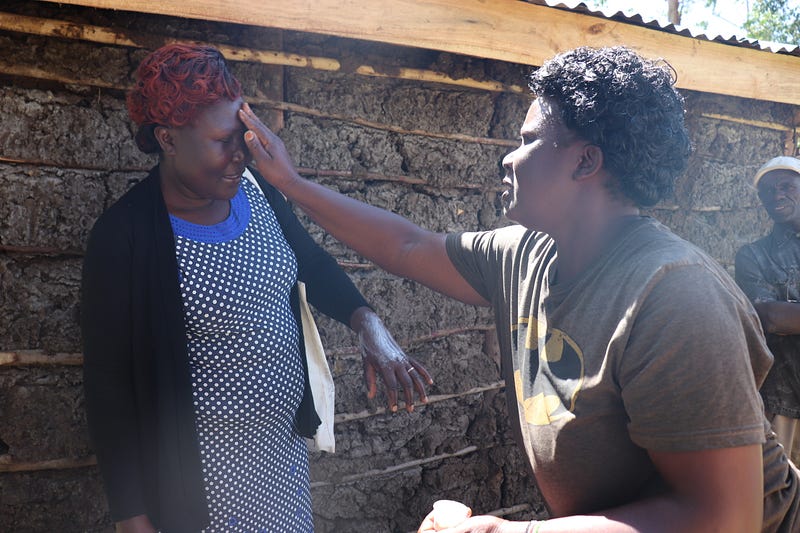 Elizabeth Kamboy applies her handmade lotion to Village Enterprise Field Associate Carolyne Wafula’s face.
