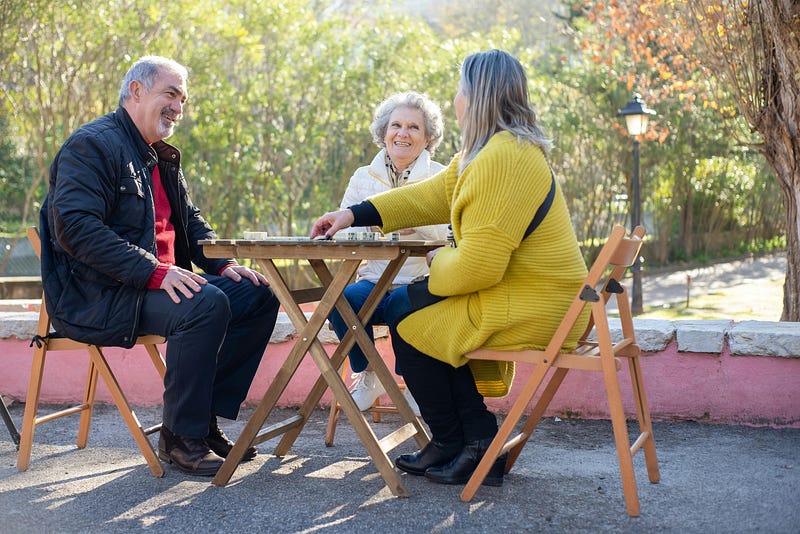 Senior citizens playing chess in garden.