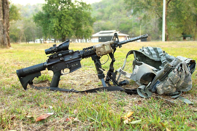 Automatic rifle on the ground next to military gear