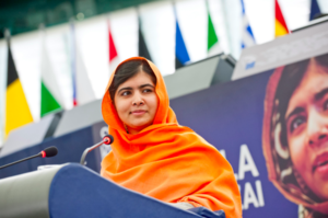 A photo of Malala Yousafzai standing at a podium.
