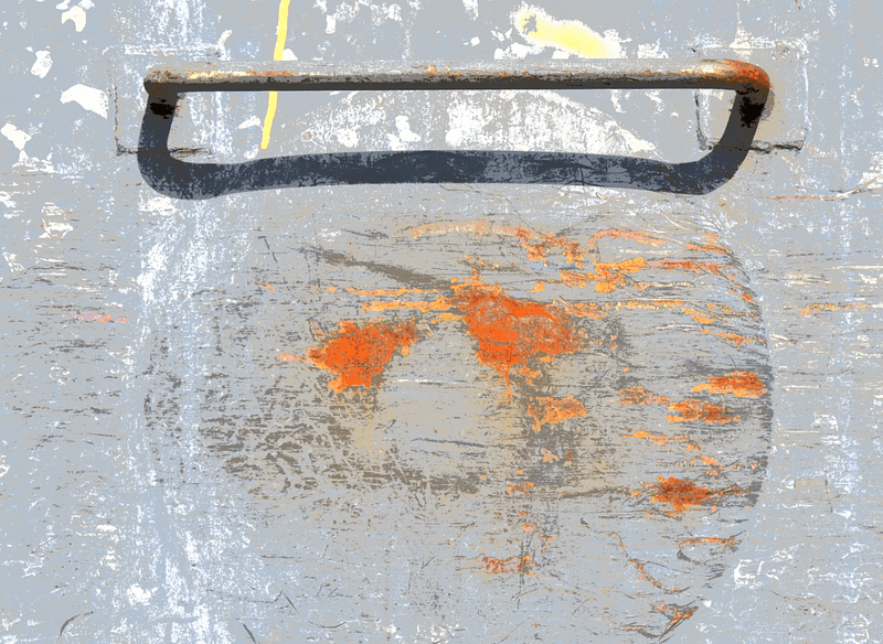 Closeup of a thin metal handle above a rusty gray circle