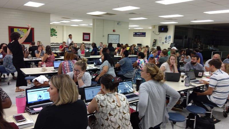 A room of teachers look at laptops during a CommonLit professional development session. 