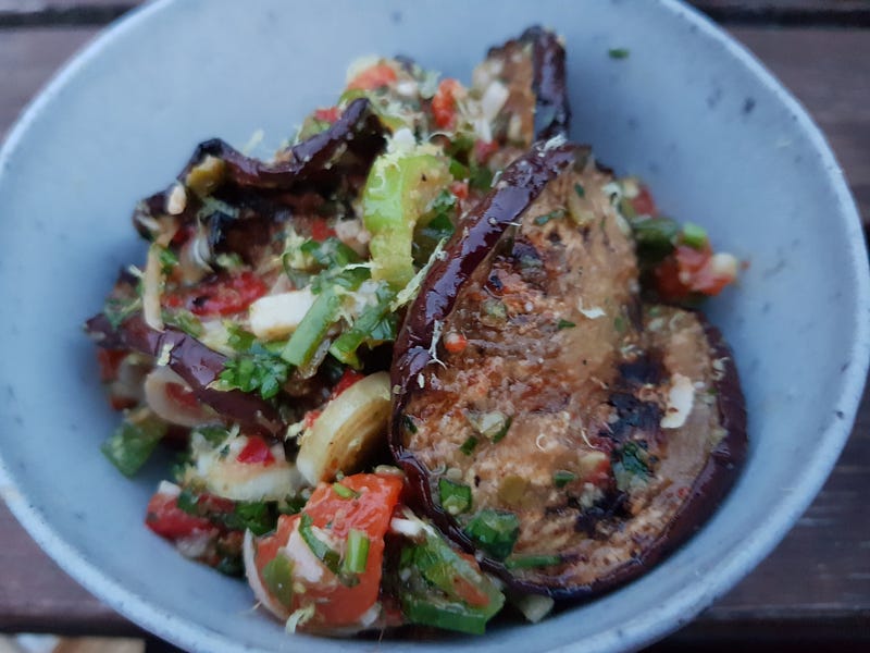 A bowl filled with a grilled eggplant and pepper salad