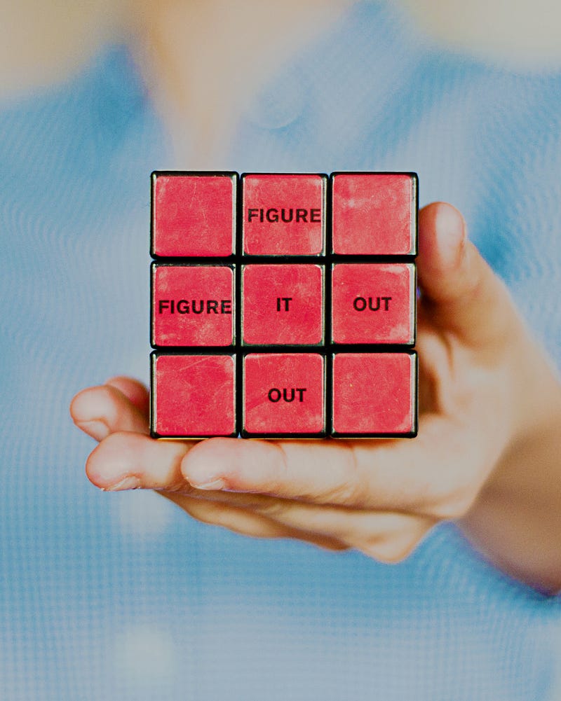 A red rubix cube with the words “Figure”, “It” and “Out” written on the side.