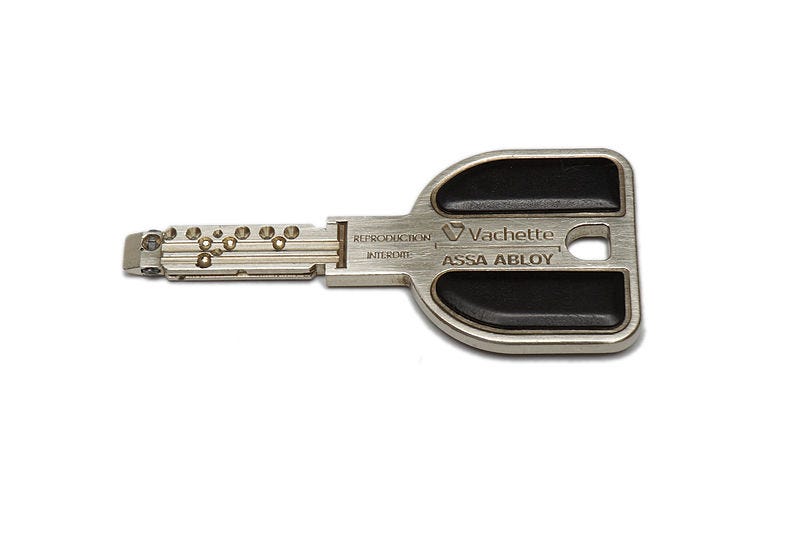 A photograph of a small silver key on a white background