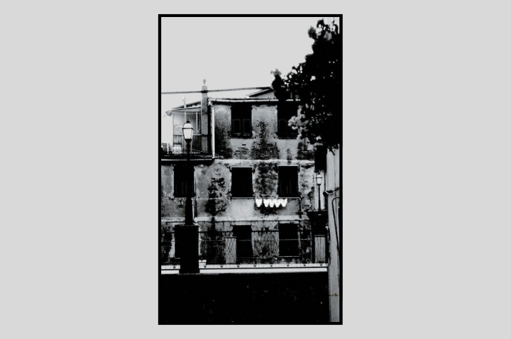 Author monochrome photograph of an old Italian building with a line of white underpants hanging out to dry