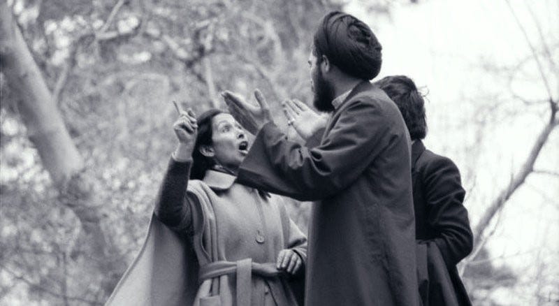 A young Iranian woman wearing a trench coat and exposed hair fiercely argues with an Iranian Muslim clergyman on March 8th, 1979.