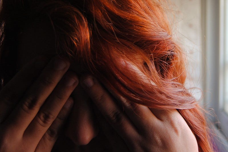 Exhausted person holds head in hands.