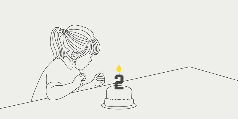 Girl blowing out a number two candle on a cake.
