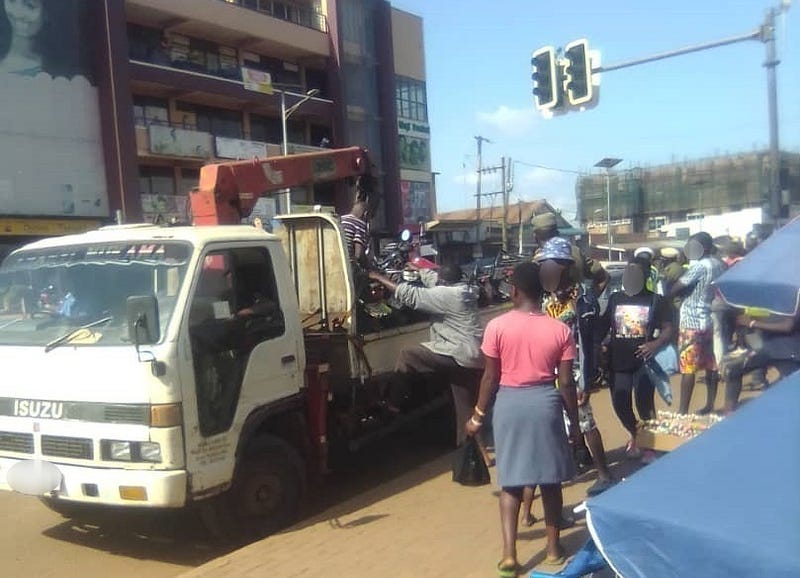 Loading impounded motorcycles into the breakdown truck. Credit: Kalungi James.