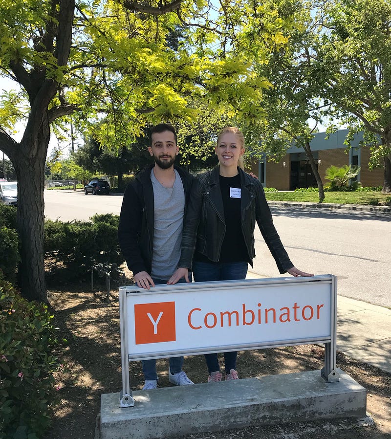 Mahyar Raissi and Daryna Kulya standing in front of Y Combinator sign