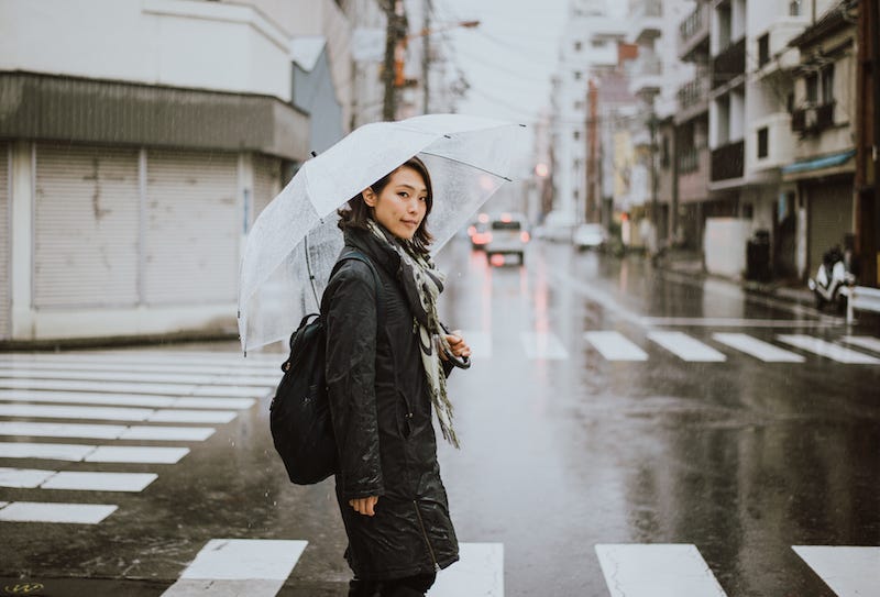 A woman in Japan walks with an umbrella during the rainy season