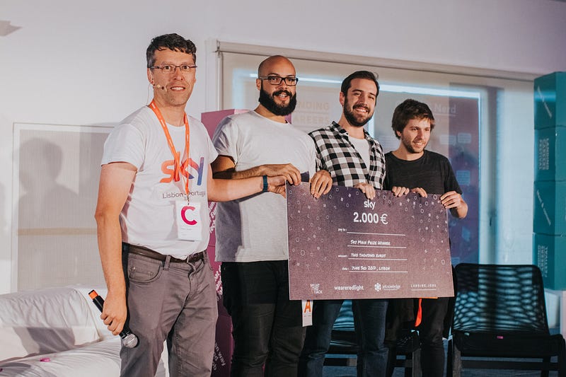Four people holding a 2.000€ check