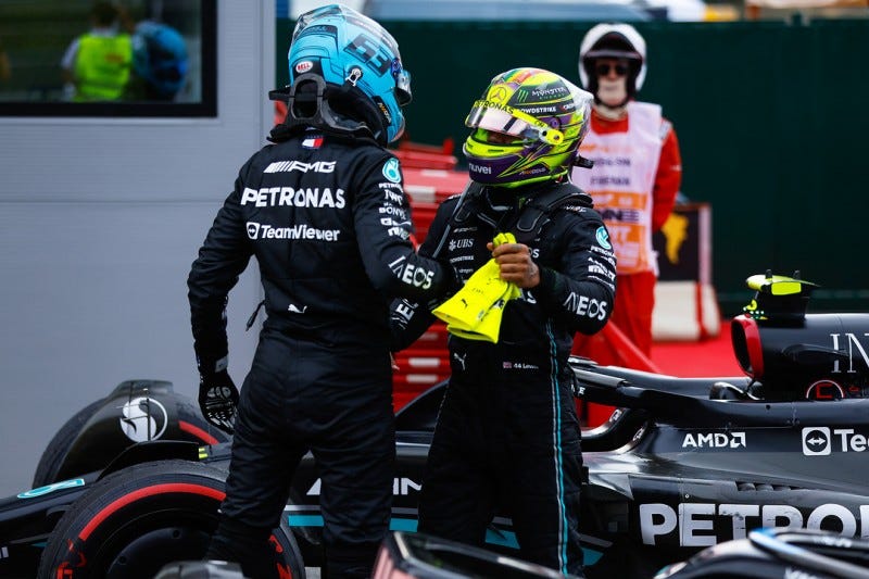 Russell and Hamilton are congratulating each other having just stepped out of their cars, still wearing helmets.