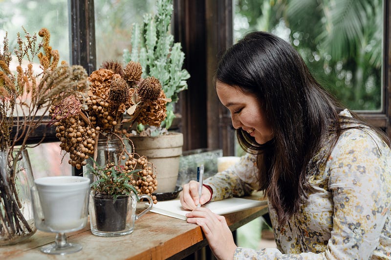 A smiling women writing happily in her diary.