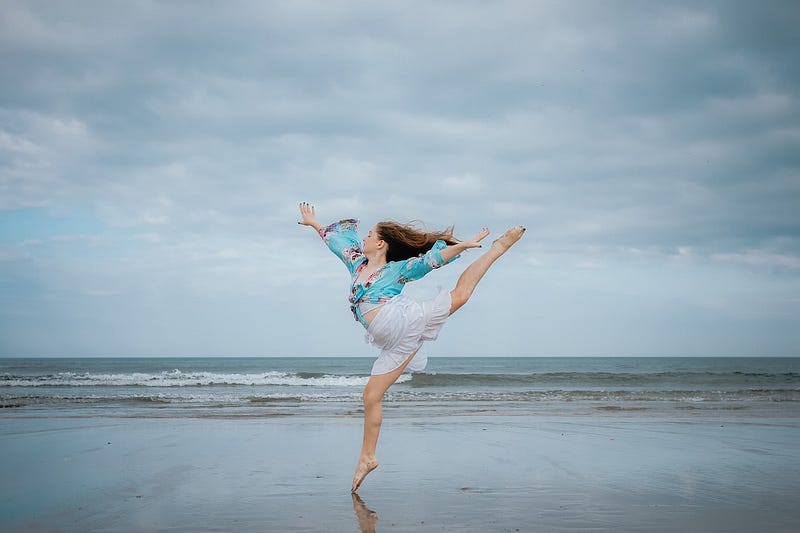 A girl wearing blue top and white skirt posing on the sea shore.